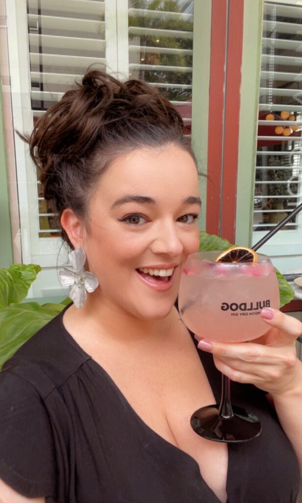 Elizabeth Best: girl with brown hair in an updo with a cocktail wearing KVD Good Apple Foundation with a glowing complexion