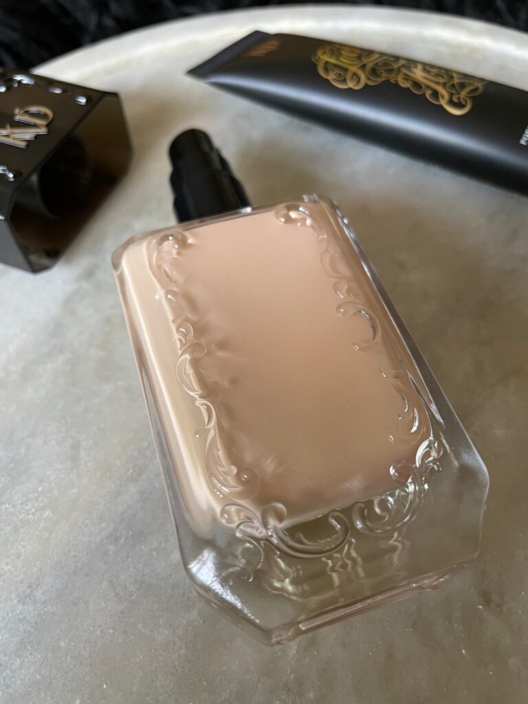 Up close image of KVD Beauty Good Apple foundation glass bottle with intricate designs