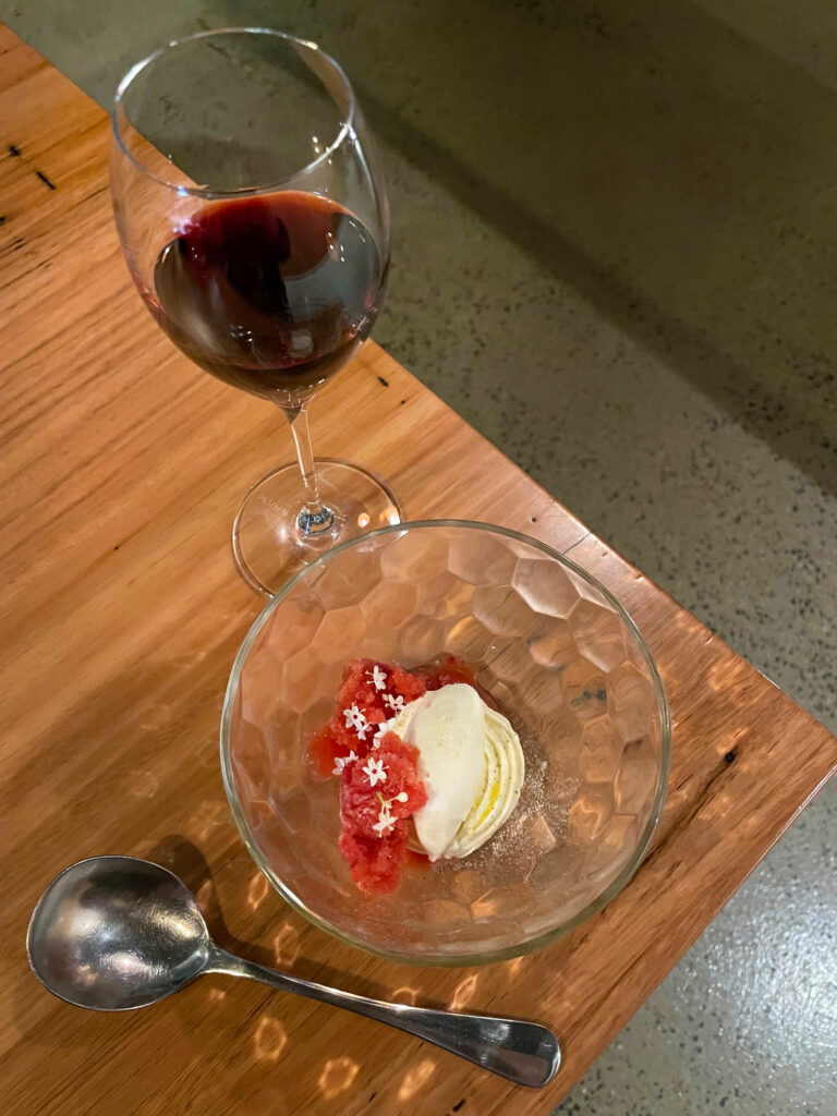 glass of red wine alongside a small bowl of plum granita and a quenelle of vanilla ice cream at c'est bon
