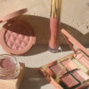 Mellow Cosmetics sitting on stone, including eyeshadow palette, blush, lip gloss and pot eyeshadow in neutral tones