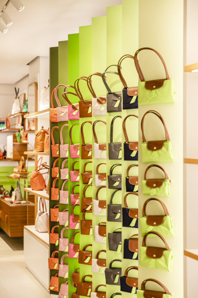 Longchamp totes lined up on a wall.