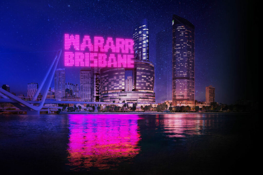 Pink drones above the Brisbane River spell out wararr brisbane. 