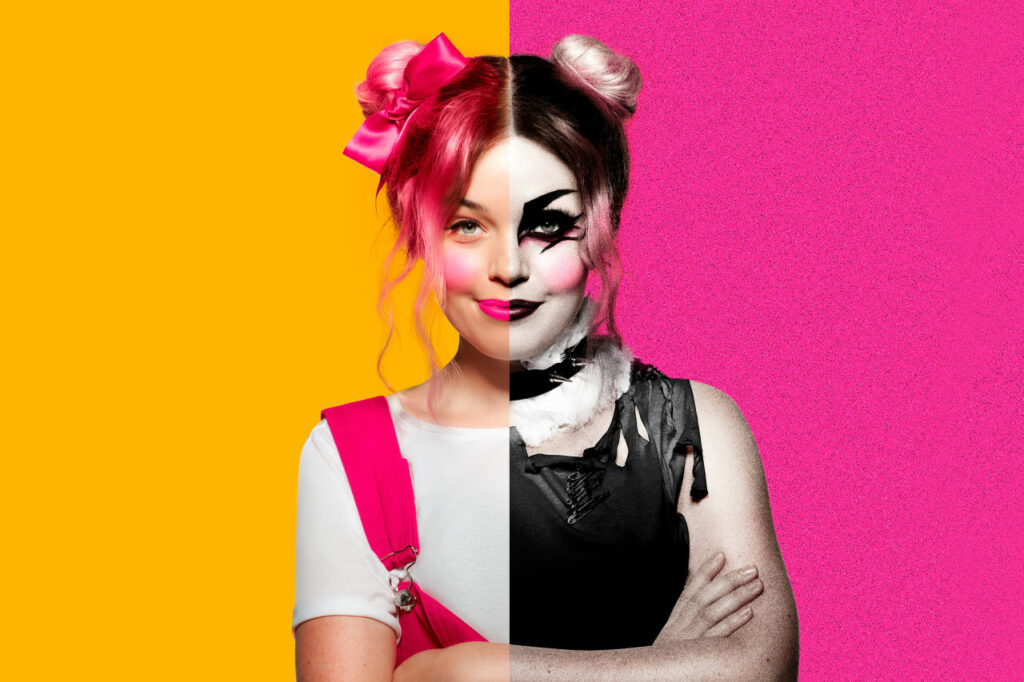 A woman, one side of her is dressed like a children's performer with cheery pink hair, and one side is dressed up in black clothes with KISS band makeup for Bananaland in Brisbane Festival