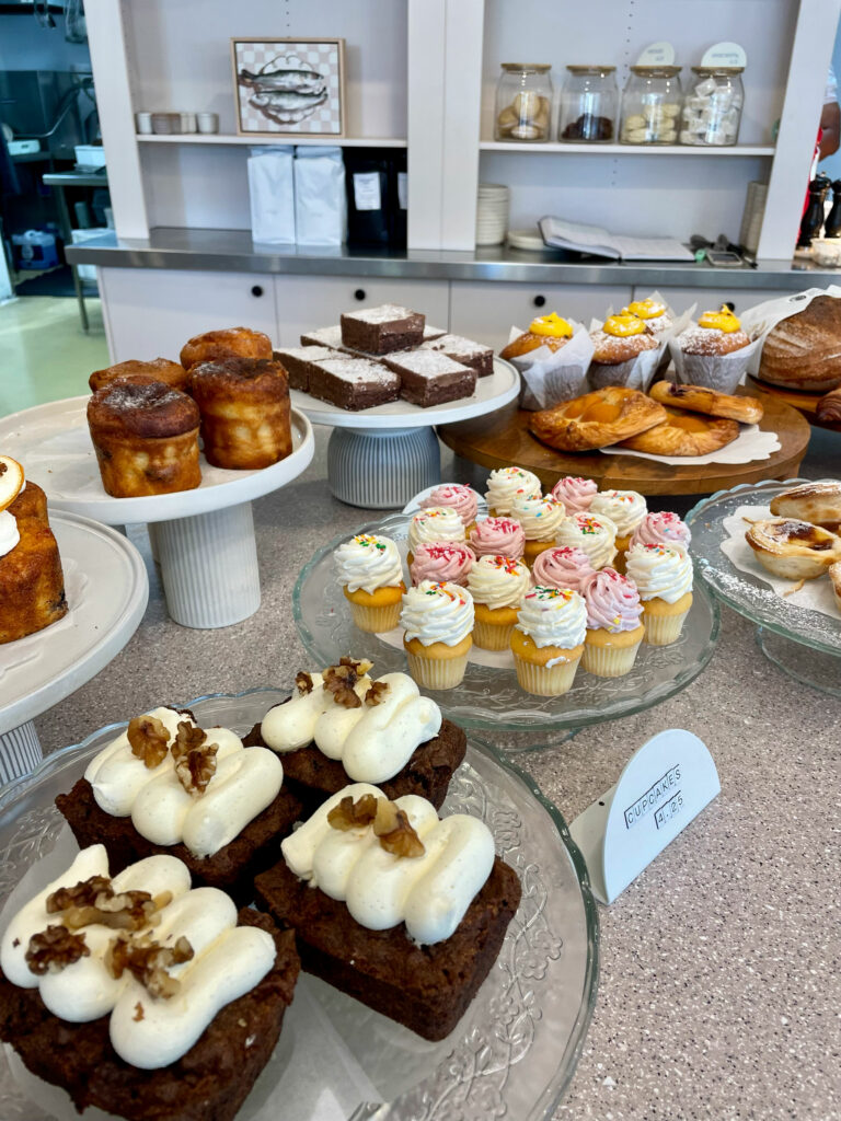 Countertop covered with little cupcakes, tarts, pastries and muffins. 