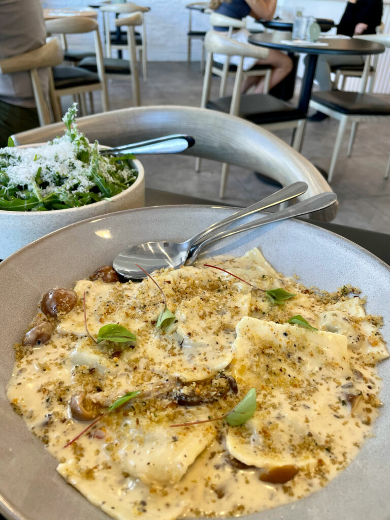 Foreground of wild mushroom ravioli and a rocket salad in the background.