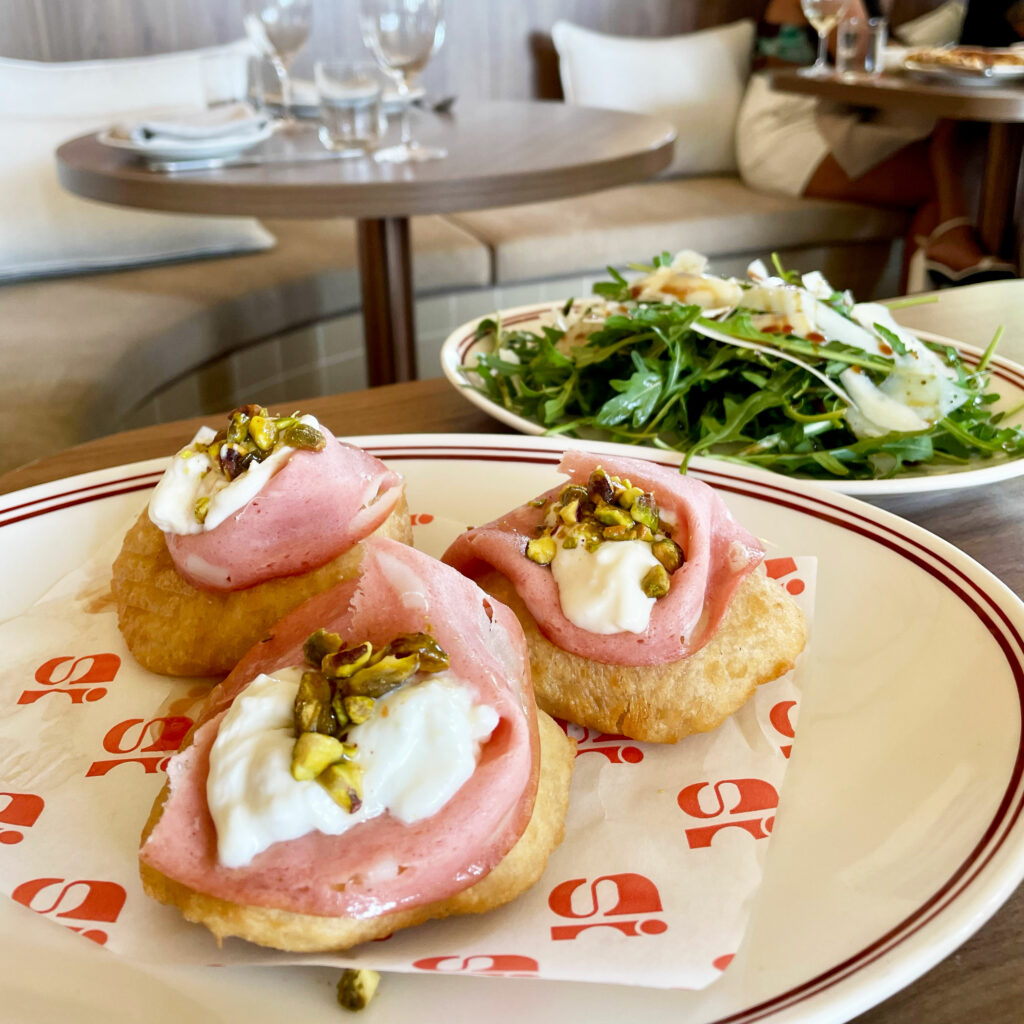 Gnocco fritto at the front of the picture with a rocket salad behind