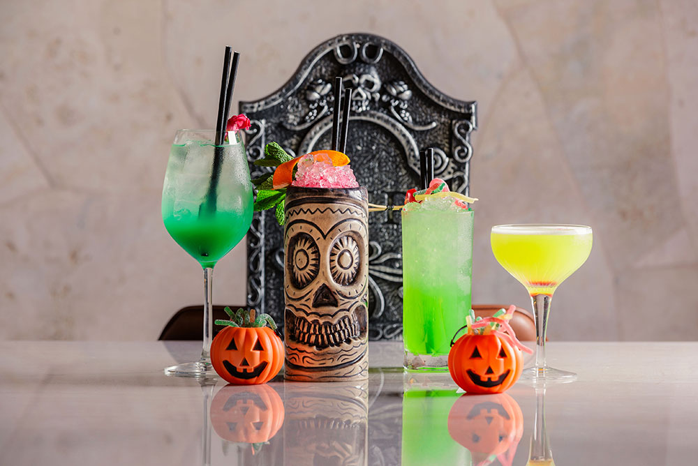 halloween themed cocktails with a grave stone behind them