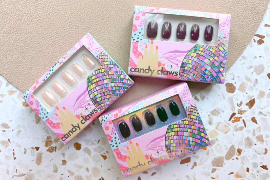 Three pairs of Candy Claws press on nail sets in their boxes on terazzo background