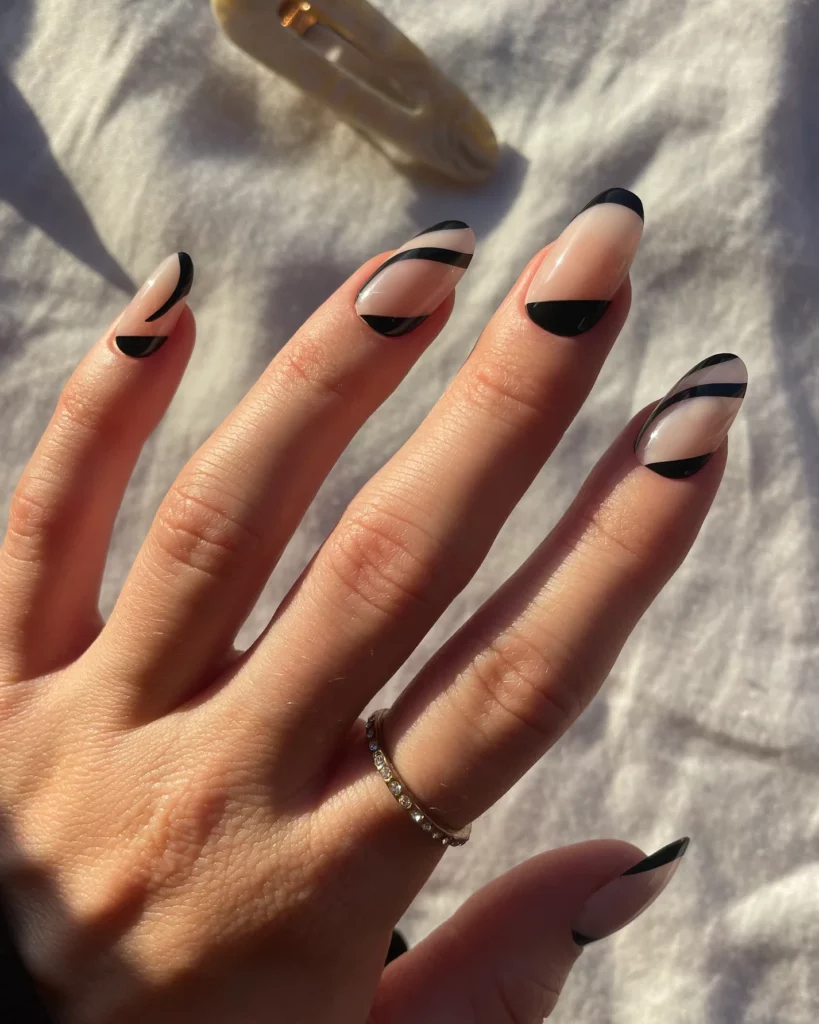A hand wearing press-on nails with black swirls on them.