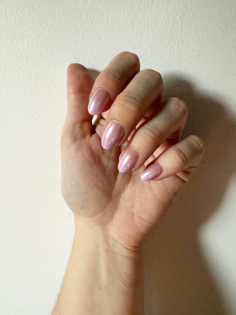 a hand wearing shiny pink press on nails 