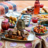 A table with a traditional Turkish tablecloth, filled with meat skewers, salads, pide and cocktails at Ahmet's Turkish.