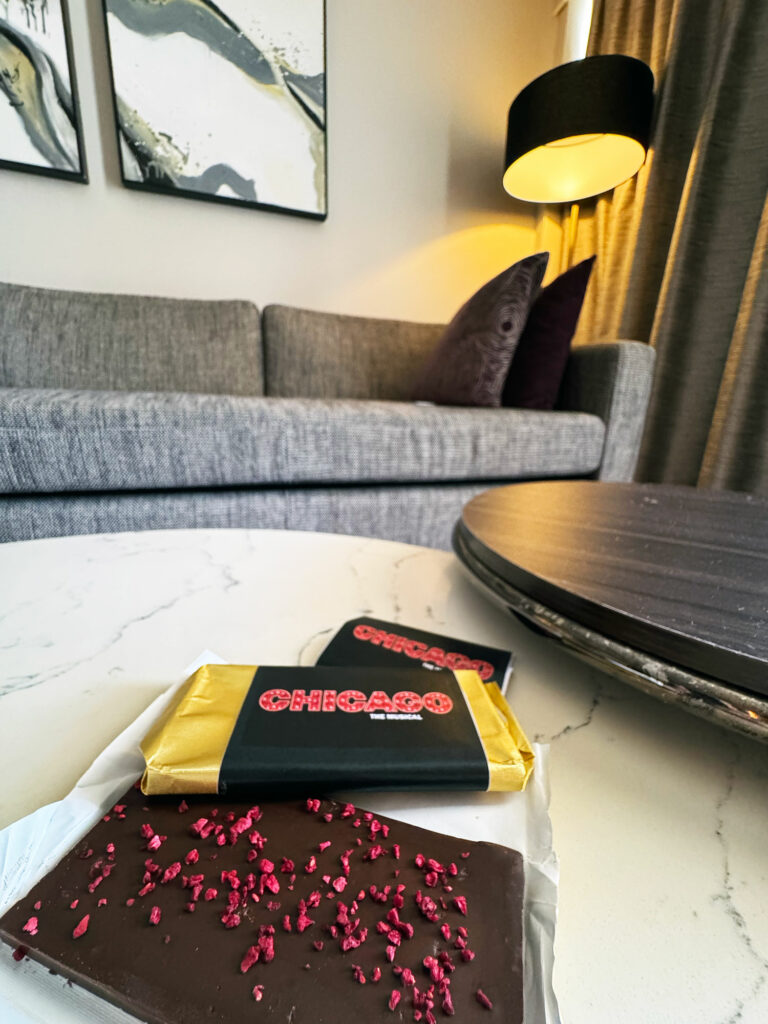 Two bars of chocolate with Chicago musical wrappers on a marble table in front of a couch
