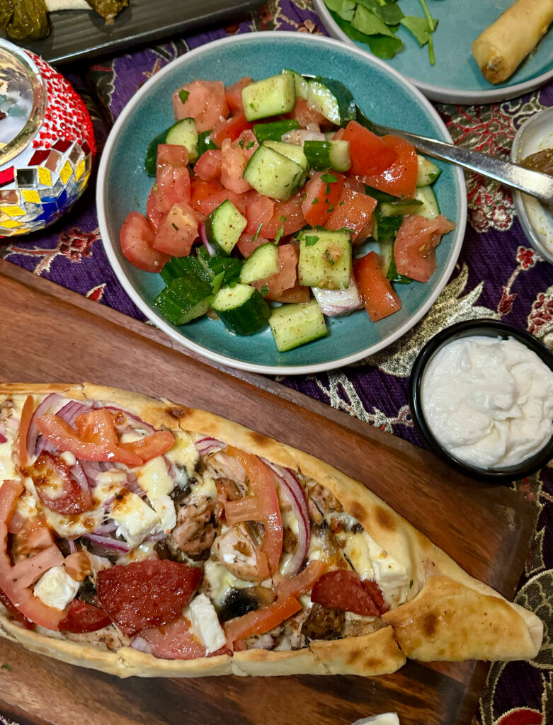 A top down image of a mediterranean salad and Turkish pide with chorizo, tomato and red onion at Ahmets. 