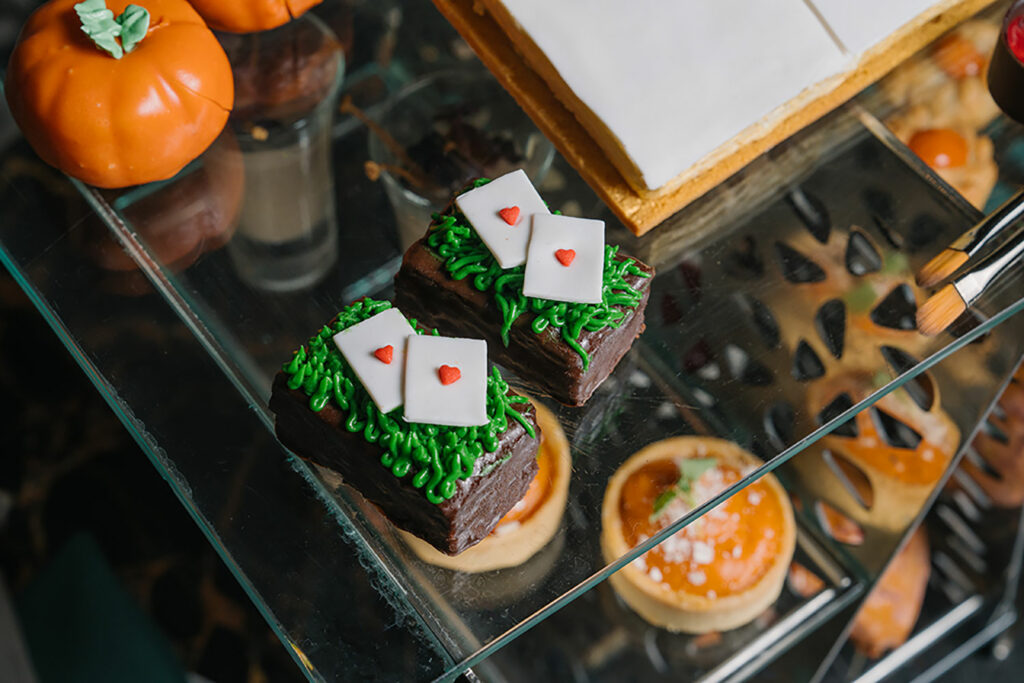 Chocolate brownies with green squiggly icing that looks like grass, topped with fondant playing cards.