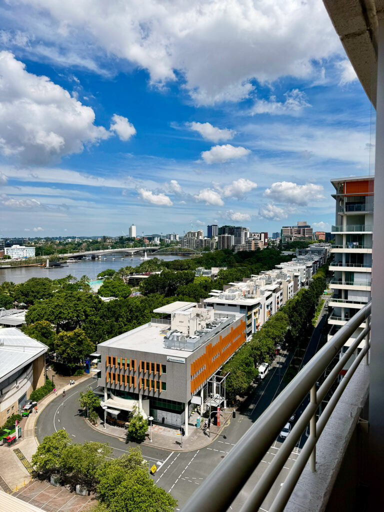 A view of South Bank from the balcony of Rydges South Bank, including rows of shops and the brisbane river