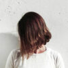 A woman with a brown bob cut has her head turned away from the camera so we can't see her face.