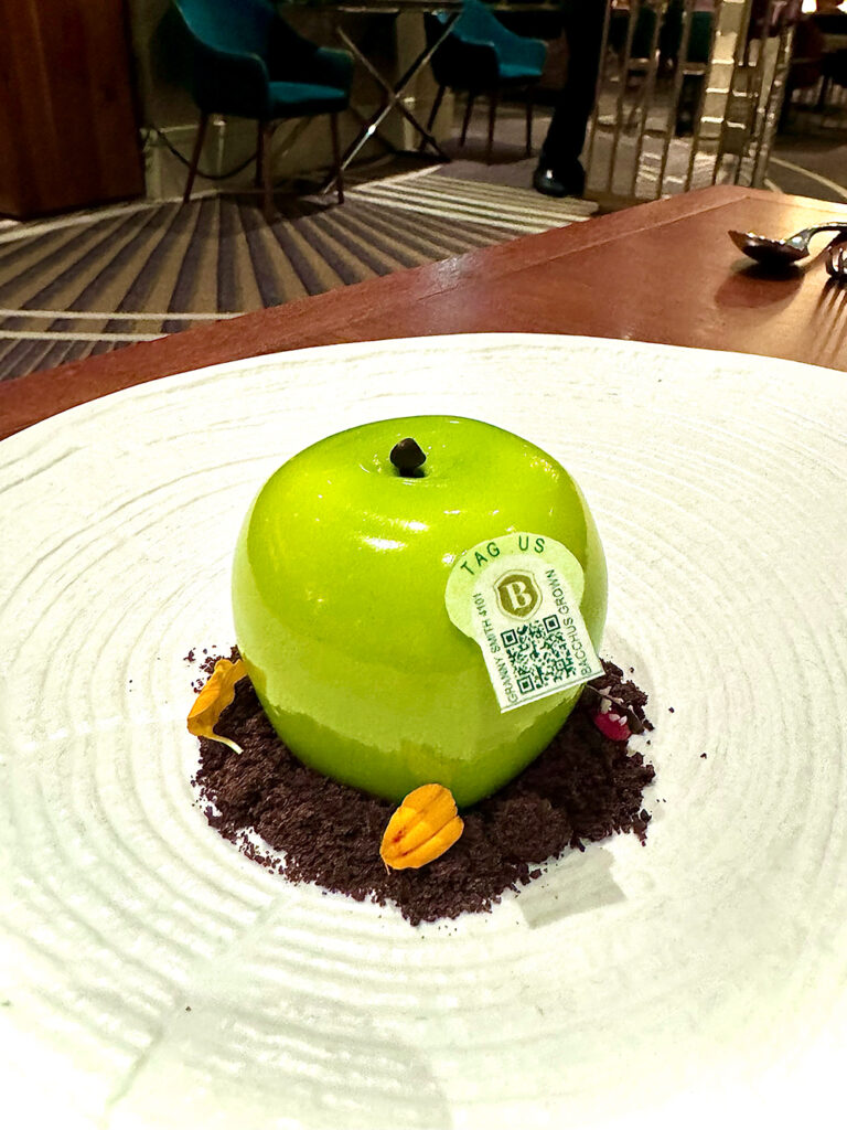 Bacchus famous apple dessert that resembles a granny smith apple in chocolate dirt sits on a white plate