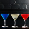 Three martini glasses sit side by side, one blue one white and one red, making a french flag