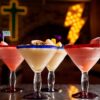 A lineup of several margaritas with neon signs behind them