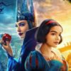 Movie image featuring gal gadot as the evil queen holding an apple and snow white looking off to the right