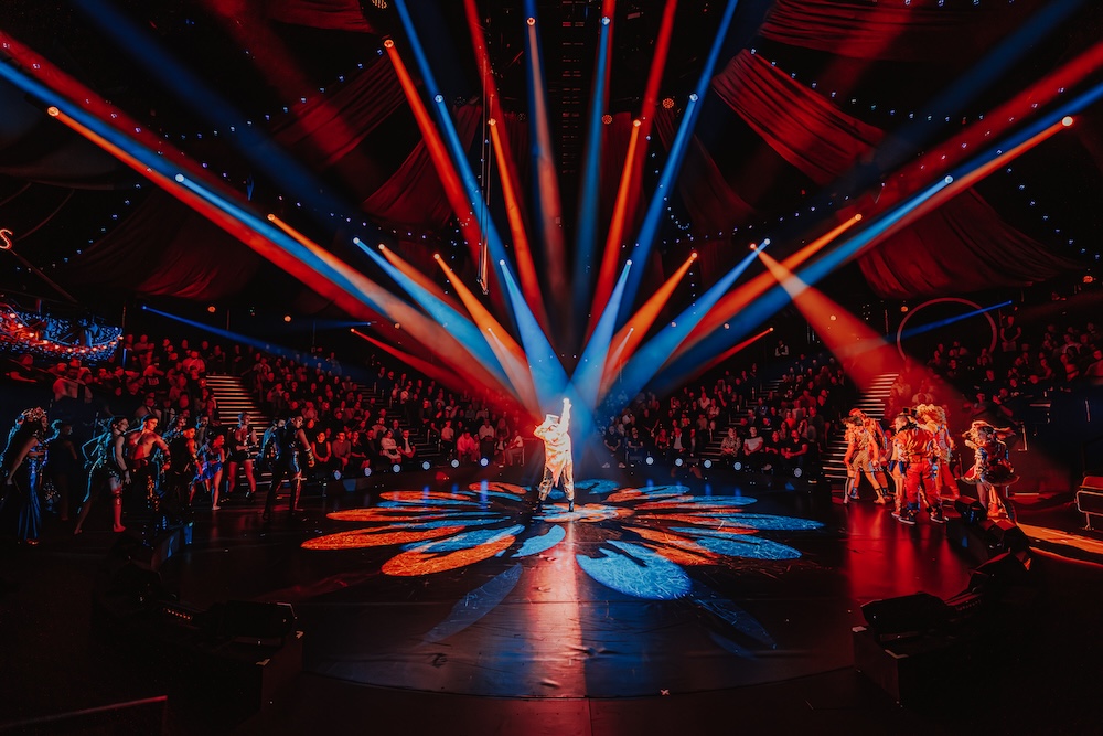 A massive new Greatest Showman live spectacular is heading to Brisbane Greatest showman red and blue spotlights on one person in the middle of a circus ring